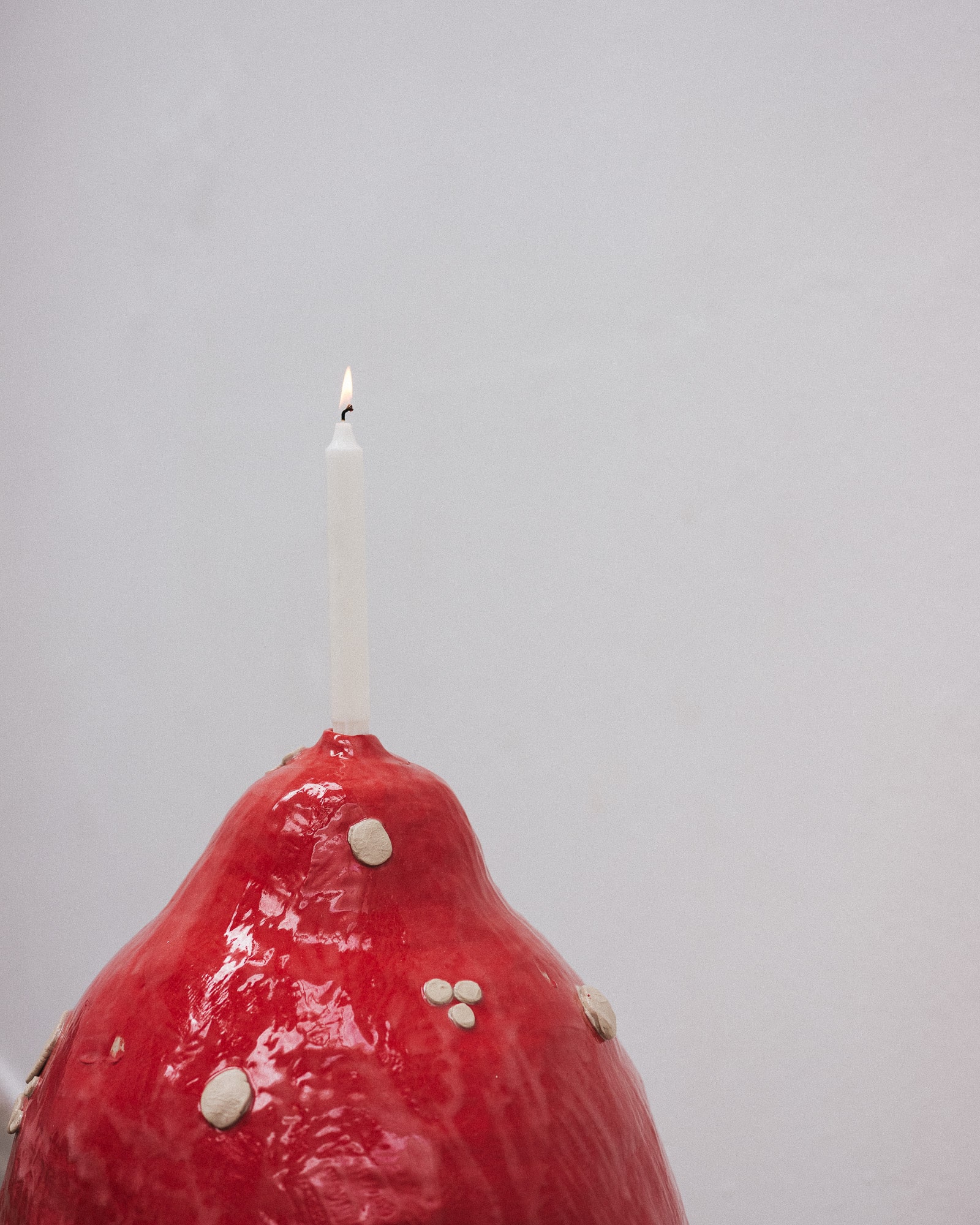 a close-up of a ceramic candle holder in a shape of a huge, human sized red mushroom